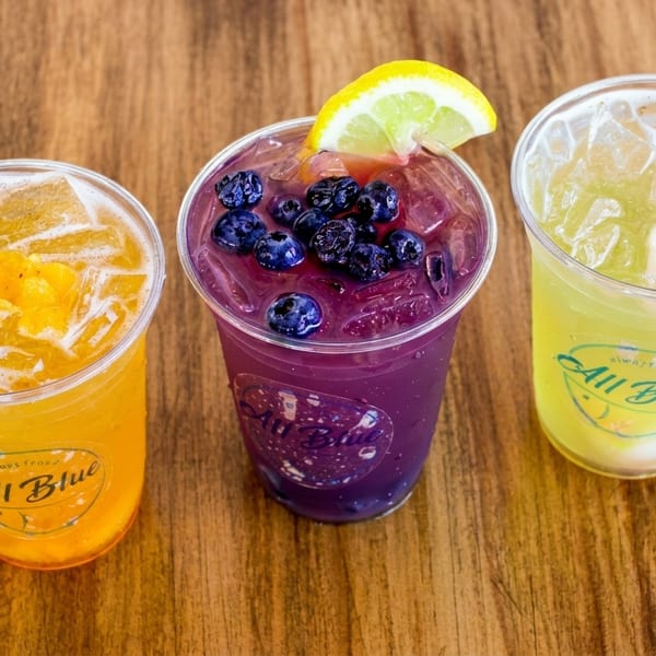 Three "All Blue" iced drinks: yellow mango, purple blueberry lemon, and light yellow lychee.