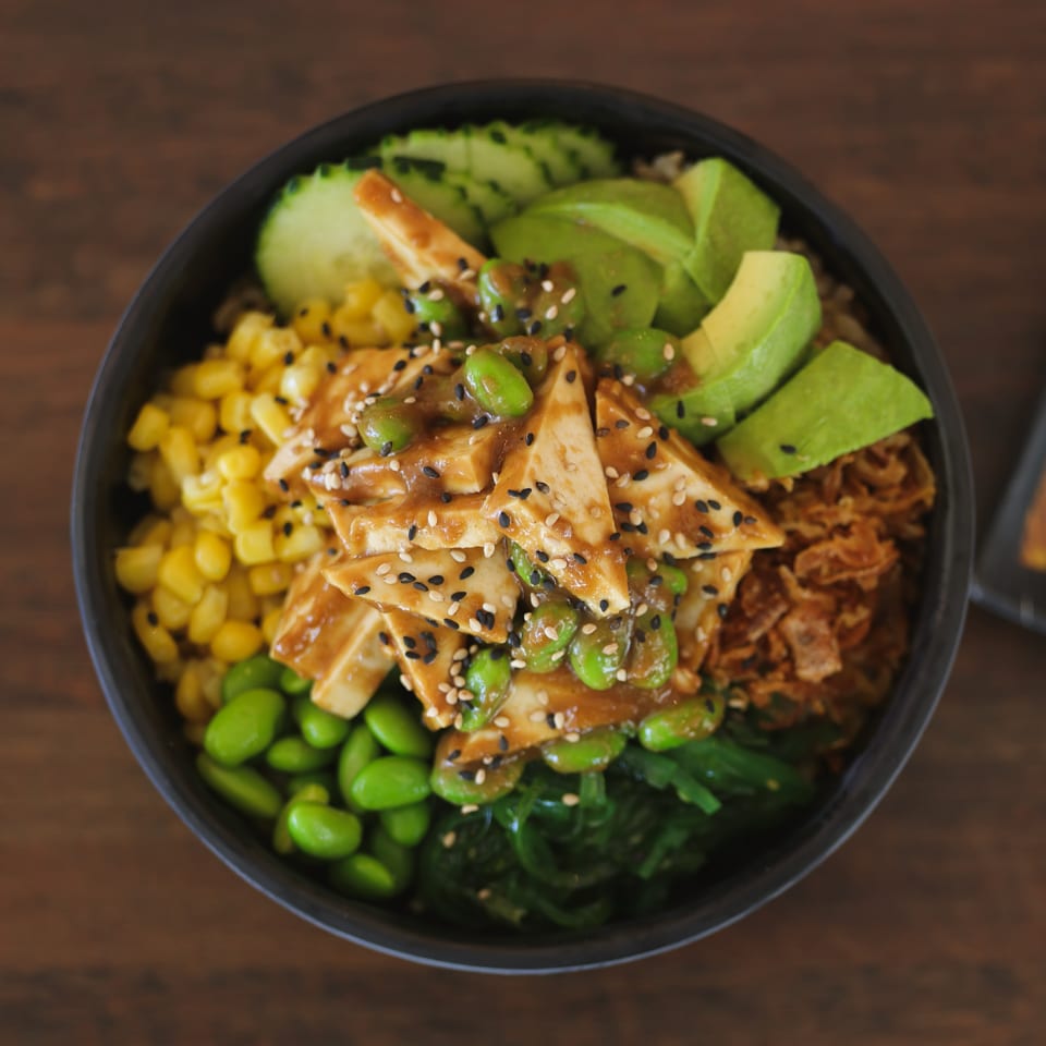 Teriyaki tofu poke bowl with avocado, edamame, corn, cucumber, seaweed, and crispy onions.