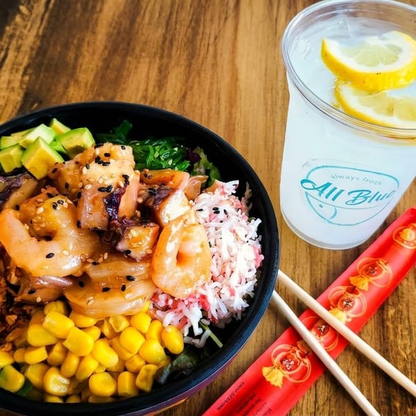 All Blue poke bowl with shrimp, avocado, corn, and crab, served with lemonade and chopsticks.