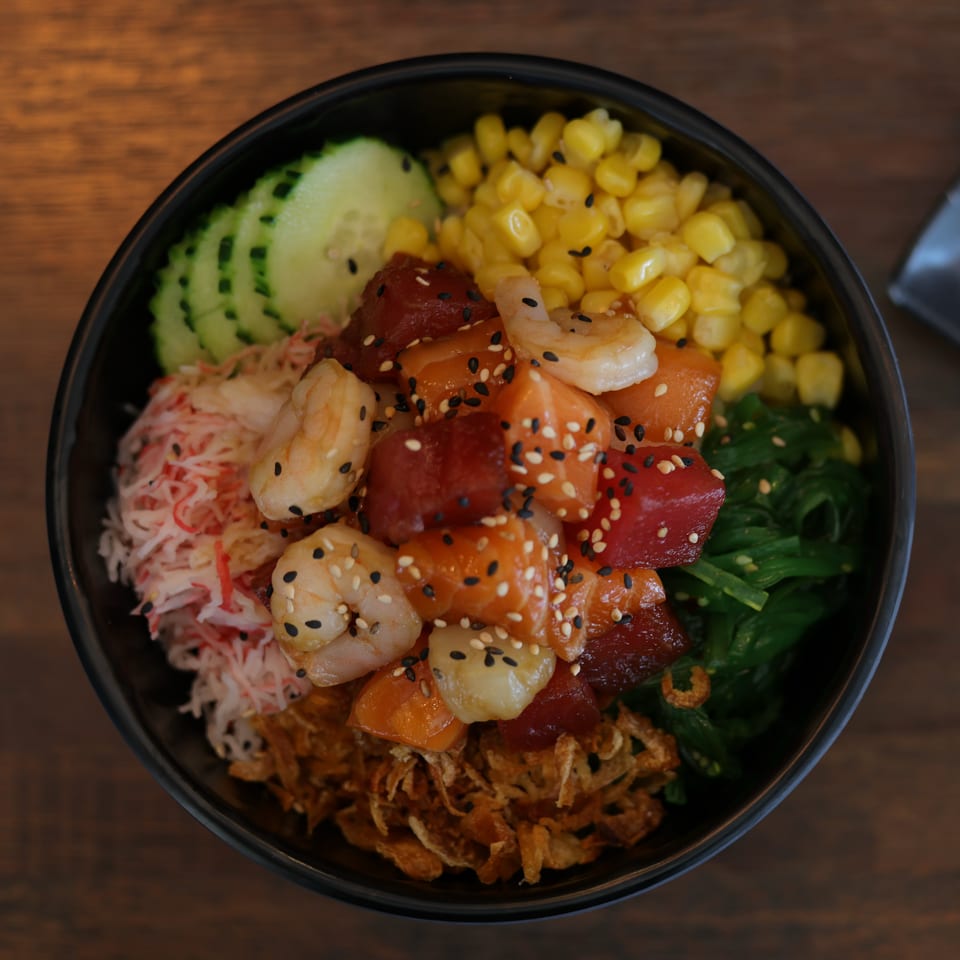 Poke bowl with tuna, salmon, shrimp, crab, corn, cucumber, seaweed, and crispy onions.